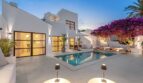 Außenpool der Traumvilla in Sol de Mallorca bei Dämmerung mit weißer Fassade und blühender Bougainvillea