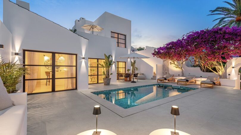 Außenpool der Traumvilla in Sol de Mallorca bei Dämmerung mit weißer Fassade und blühender Bougainvillea