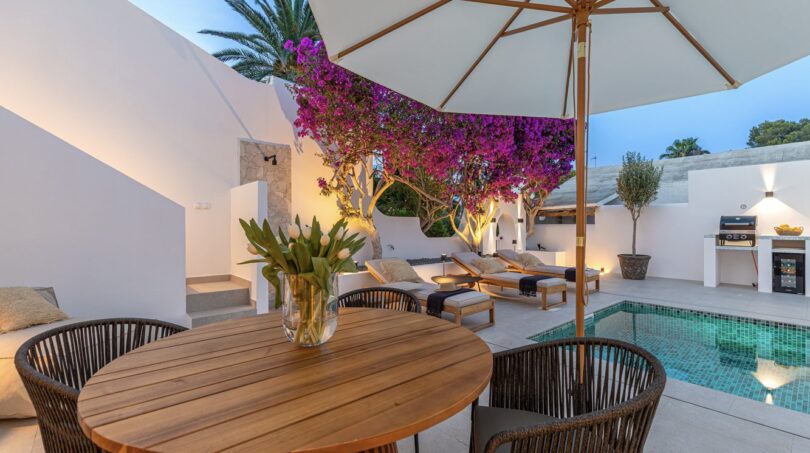 Traumvilla Sol de Mallorca: Elegante Terrasse mit Pool, Loungebereich und blühender Bougainvillea bei Abenddämmerung.