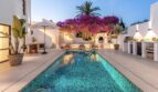 Traumvilla Sol de Mallorca: Beleuchteter Pool mit Mosaikfliesen, Bougainvillea und Außenküche im Abendlicht.