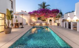 Traumvilla Sol de Mallorca: Beleuchteter Pool mit Mosaikfliesen, Bougainvillea und Außenküche im Abendlicht.