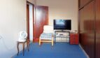 Wohnzimmer mit blauem Teppich, Sessel, Flachbild-TV und großem Holzschrank in Palma de Mallorca