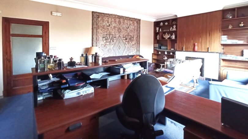 Geräumiges Arbeitszimmer mit Holzschreibtisch, eingebautem Regal, Teppich an der Wand und Kamin in Palma
