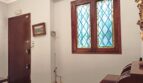 Eingangsbereich mit Holztür, Bleiglasfenster und antikem Mobiliar in renovierungsbedürftiger Altbauwohnung in Palma.