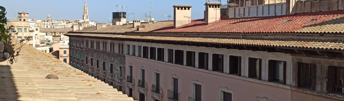 Dachterrasse mit Wäscheleine und Blick auf historische Altstadt von Palma de Mallorca bei blauem Himmel.