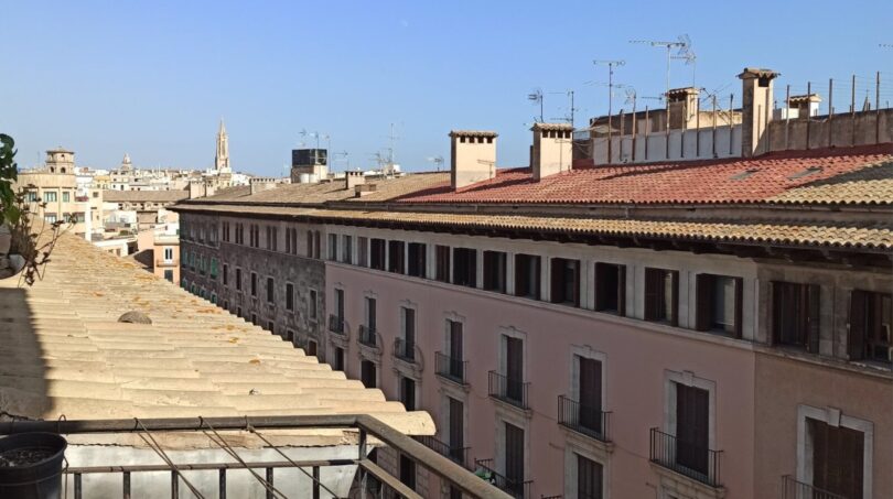 Dachterrasse mit Wäscheleine und Blick auf historische Altstadt von Palma de Mallorca bei blauem Himmel.