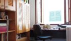 Arbeitszimmer mit Holzeinbauschrank, Schreibtisch am Fenster und schwarzem Bürostuhl in Palma-Wohnung.