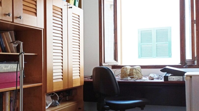 Arbeitszimmer mit Holzeinbauschrank, Schreibtisch am Fenster und schwarzem Bürostuhl in Palma-Wohnung.