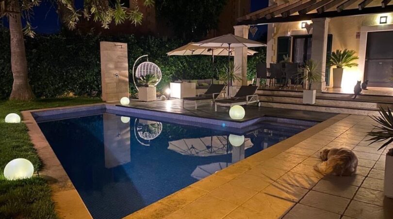 Beleuchteter Außenpool bei Nacht mit Loungebereich, Hängestuhl und Kugelleuchten, Einfamilienhaus Llucmajor