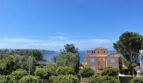 Außenansicht Villa in Llucmajor mit Meerblick, mediterraner Architektur und üppiger Begrünung im Vordergrund.