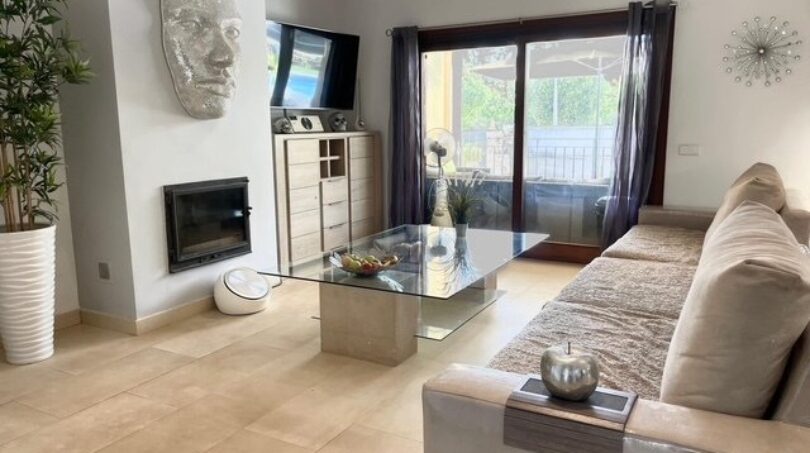 Helles Wohnzimmer mit Glascouchtisch, Kamin, Sofa und Zugang zur Terrasse im Einfamilienhaus Llucmajor