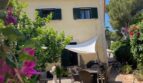 Sonnige Terrasse mit Sonnensegel und Gartenmöbeln am mediterranen Einfamilienhaus in Llucmajor, umgeben von Bougainvillea.