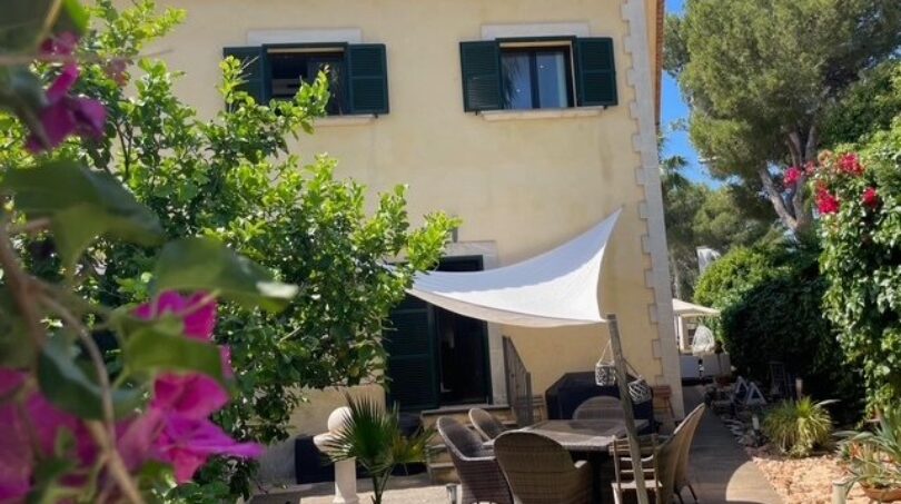 Sonnige Terrasse mit Sonnensegel und Gartenmöbeln am mediterranen Einfamilienhaus in Llucmajor, umgeben von Bougainvillea.