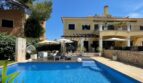 Außenansicht: Mediterrane Villa in Llucmajor mit blauem Pool, Sonnenterrasse und Lounge-Bereich unter Sonnenschirmen.