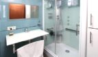 Modernes Badezimmer mit Glasdusche, Wandspiegel und blauer Fliesenverkleidung in exklusiver Hafenwohnung El Toro