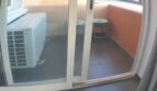 Balkon der Luxuswohnung in Port Adriano mit Klimaanlage, Sitzgelegenheit und Blick ins Grüne