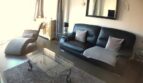 Elegantes Wohnzimmer mit schwarzem Ledersofa, Glascouchtisch und Spiegel in exklusiver Hafenwohnung El Toro