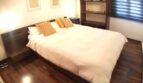 Elegantes Schlafzimmer mit Doppelbett, Holzboden und modernem Bücherregal in exklusiver Wohnung am Yachthafen Port Adriano.