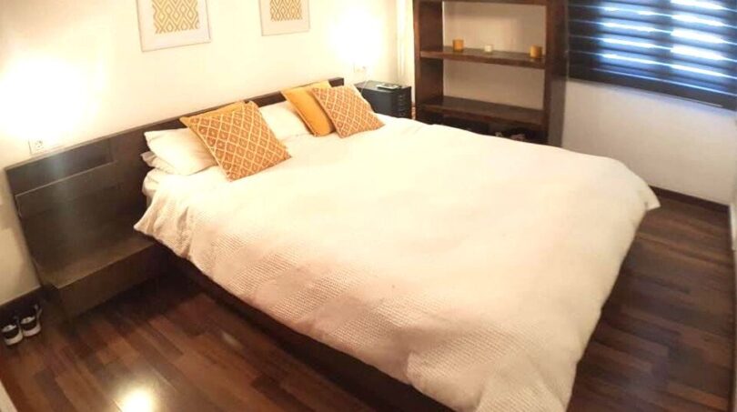 Elegantes Schlafzimmer mit Doppelbett, Holzboden und modernem Bücherregal in exklusiver Wohnung am Yachthafen Port Adriano.