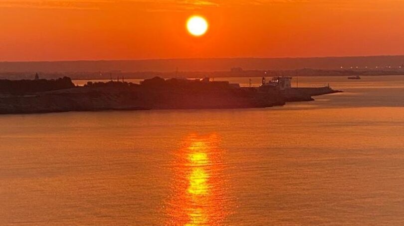 Spektakulärer Meerblick bei Sonnenuntergang mit orangenem Himmel, Wasserreflexion und Küstensilhouette in Illetas, Mallorca.