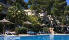 Luxuriöser Außenpool mit Liegestühlen, Palmen und mediterraner Hotelanlage in Illetas, Mallorca.