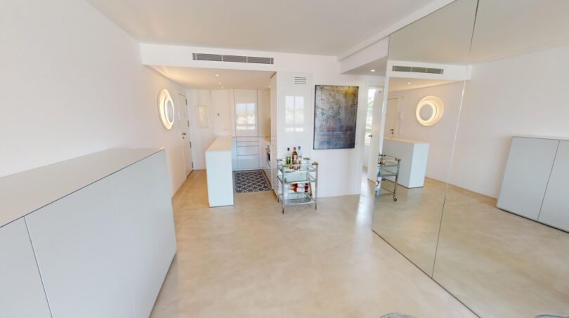 Helles Wohnzimmer der Luxuswohnung in Illetas mit weißen Einbauschränken, Bar-Trolley und großem Wandspiegel