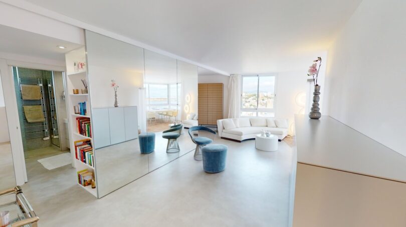 Helles Wohnzimmer mit Spiegelwand, blauen Hockern, weißem Sofa und Meerblick in Luxuswohnung Illetas
