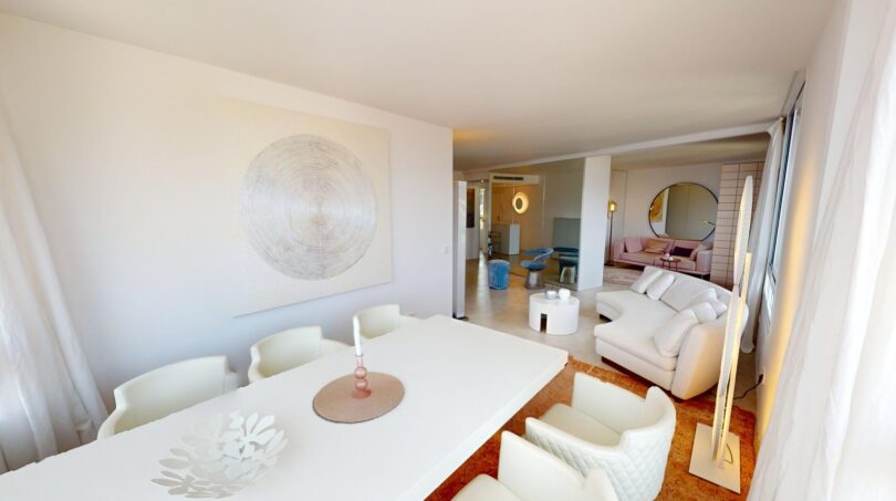 Helles Wohn-Esszimmer mit weißen Möbeln, Kunstwerk und Blick in weitere Räume der Luxuswohnung in Illetas