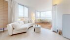 Helles Wohnzimmer mit weißem Curved-Sofa, Panoramafenster und Meerblick in exklusiver Luxuswohnung in Illetas