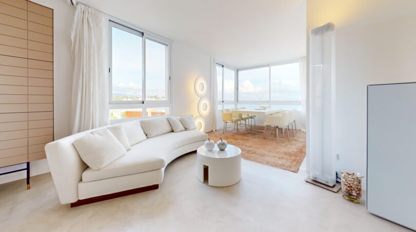 Helles Wohnzimmer mit weißem Curved-Sofa, Panoramafenster und Meerblick in exklusiver Luxuswohnung in Illetas