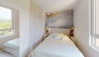 Helles Schlafzimmer der Luxuswohnung Illetas mit Doppelbett, Wandkunst und Naturblick aus großen Fenstern.