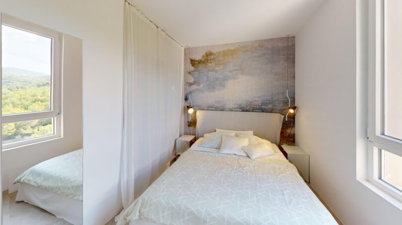 Helles Schlafzimmer der Luxuswohnung Illetas mit Doppelbett, Wandkunst und Naturblick aus großen Fenstern.