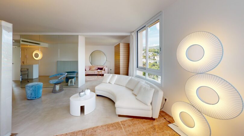 Helles Wohnzimmer mit geschwungenem weißem Sofa, runden Wandleuchten und Meerblick in Luxuswohnung Illetas
