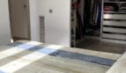 Helles Schlafzimmer mit begehbarem Kleiderschrank und gestreifter Bettwäsche im Reihenhaus Llucmajor
