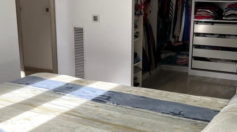 Helles Schlafzimmer mit begehbarem Kleiderschrank und gestreifter Bettwäsche im Reihenhaus Llucmajor