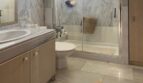 Helles Badezimmer mit Marmorverkleidung, Glasdusche, WC und Holzunterschrank im Reihenhaus Llucmajor