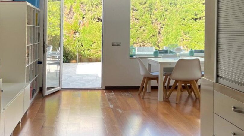 Helles Wohnzimmer mit Holzboden, Terrassenzugang und Gartenblick im modernen Reihenhaus in Llucmajor.
