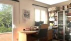 Helles Arbeitszimmer mit Holzschreibtisch, Bücherregal und großem Fenster mit Balkonzugang im Reihenhaus Llucmajor.