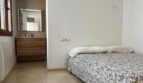 Helles Schlafzimmer mit Doppelbett, Marmorboden und angrenzendem Bad mit Holzwaschtisch im Reihenhaus Llucmajor