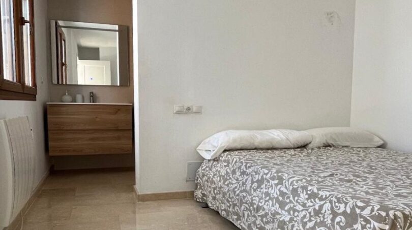 Helles Schlafzimmer mit Doppelbett, Marmorboden und angrenzendem Bad mit Holzwaschtisch im Reihenhaus Llucmajor