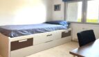 Helles Kinderzimmer mit Einzelbett, Schubladen, Schreibtisch und Fenster im Reihenhaus Llucmajor