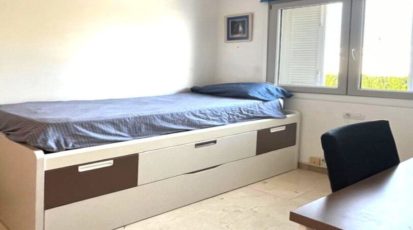 Helles Kinderzimmer mit Einzelbett, Schubladen, Schreibtisch und Fenster im Reihenhaus Llucmajor