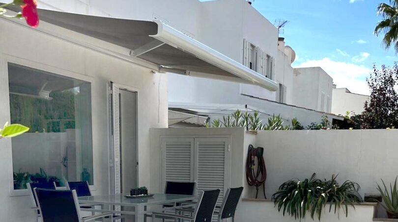 Sonnige Terrasse mit Esstisch, Markise und Pflanzen eines modernen Reihenhauses in Llucmajor
