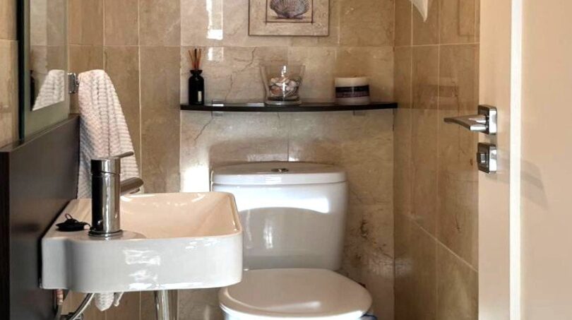Kleines WC mit Marmorverkleidung, Wandwaschbecken und Toilette unter Gewölbedecke im Reihenhaus Llucmajor