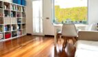 Helles Wohnzimmer mit Holzboden, Bücherregal und Gartenblick im modernen Reihenhaus in Llucmajor.