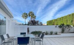 Sunny terrace with dining table, palm trees and green hedge of the townhouse in Llucmajor