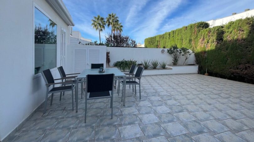 Gepflegte Terrasse mit Esstisch, Stühlen und üppigem Grün beim Reihenhaus in Llucmajor