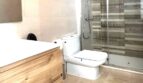 Modernes Badezimmer mit Glasdusche, WC und Holz-Waschtischunterschrank, Marmorböden, Reihenhaus Llucmajor