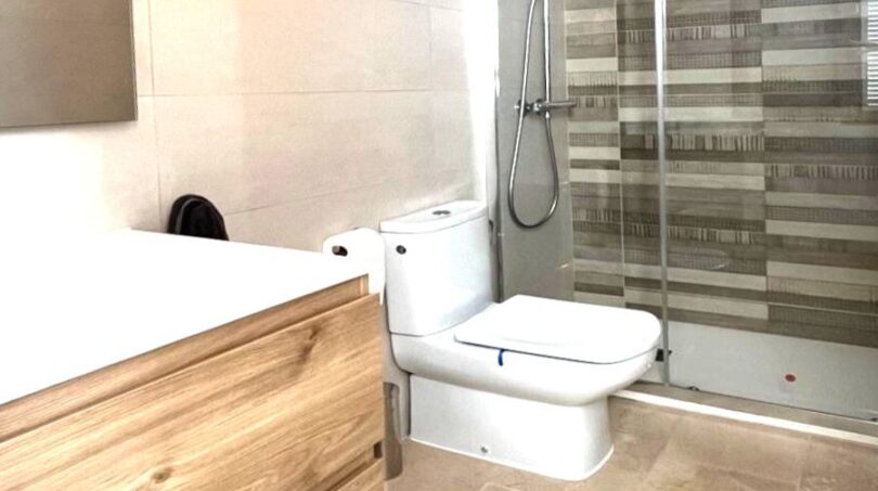 Modernes Badezimmer mit Glasdusche, WC und Holz-Waschtischunterschrank, Marmorböden, Reihenhaus Llucmajor