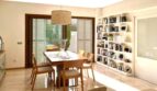 Helles Esszimmer mit Marmorboden, Holztisch, Stühlen, Bücherregal und Gartenblick im Reihenhaus Llucmajor
